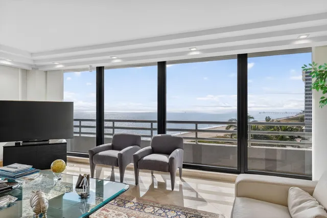 a living room with couches and a flat screen tv with a floor to ceiling window