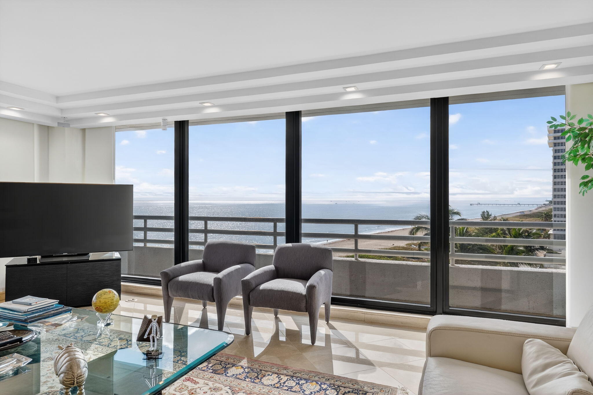 1500 South Ocean Boulevard, Unit 606 Boca Raton, FL 33432 - Photo 4 of 77 a living room with couches and a flat screen tv with a floor to ceiling window