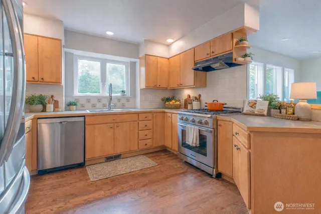 a kitchen with a sink cabinets appliances and a large window