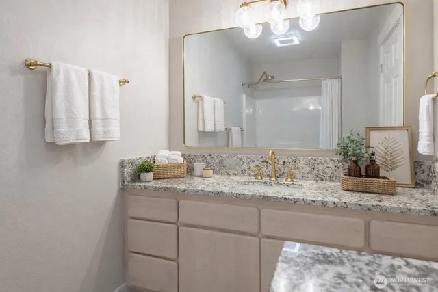 a bathroom with a granite countertop sink a mirror and a shower