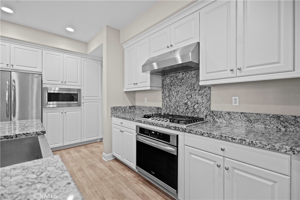 7459 Solstice Place Rancho Cucamonga, CA 91739 - Photo 40 of 57 a kitchen with stainless steel appliances granite countertop a stove a refrigerator and a white cabinets