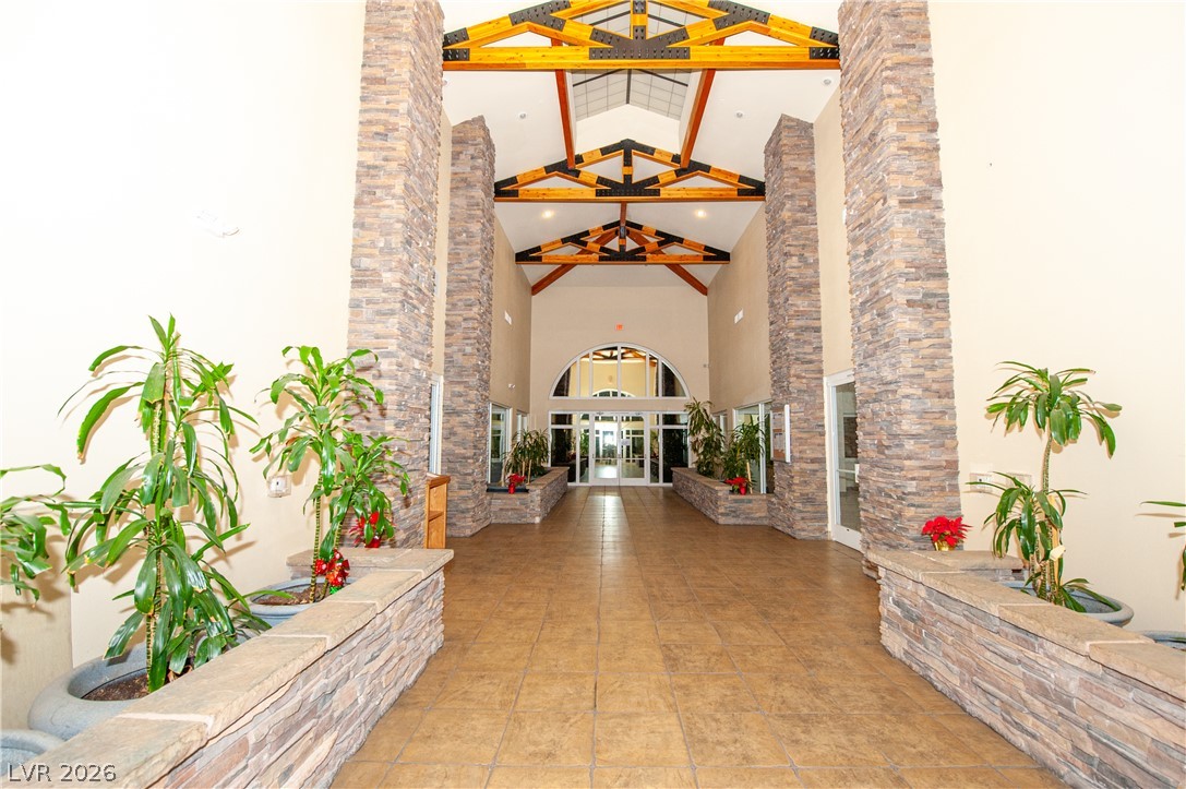 9050 West Warm Springs Road, Unit 1132 Las Vegas, NV 89148 - Photo 18 of 21 Enter a grand foyer featuring high vaulted ceilings, exposed wooden beams, and elegant stone accents.