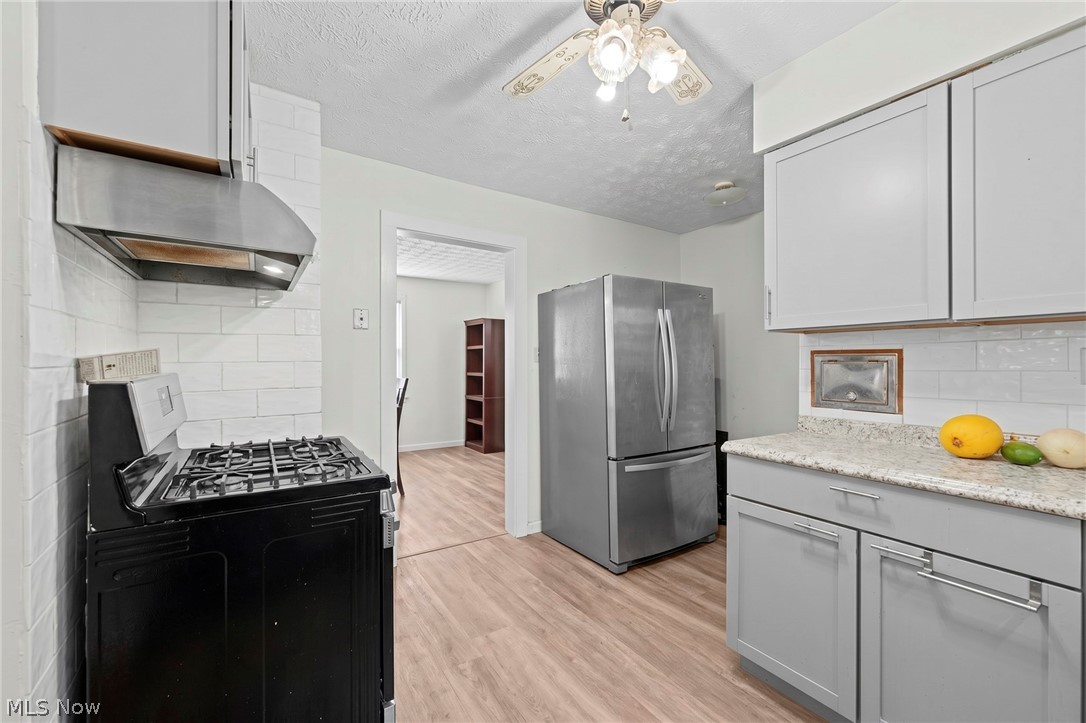 819 Keeney Street Akron, OH 44310 - Photo 22 of 24 Kitchen featuring light gray cabinetry, a stainless steel refrigerator, and a gas range with an overhead stainless steel range hood