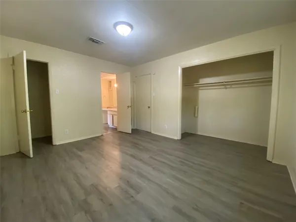 an empty room with wooden floor & closet area