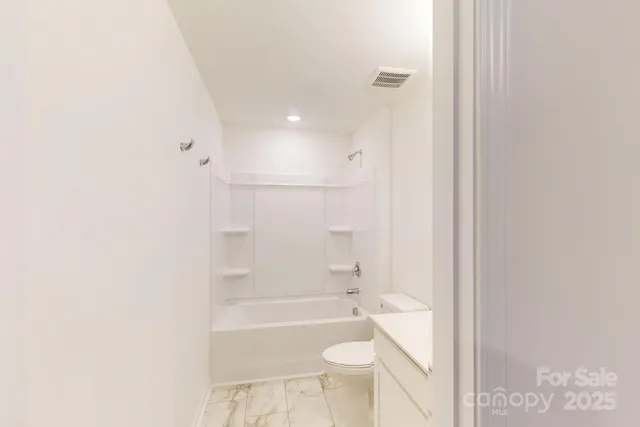 a bathroom with a granite countertop bathtub shower and toilet