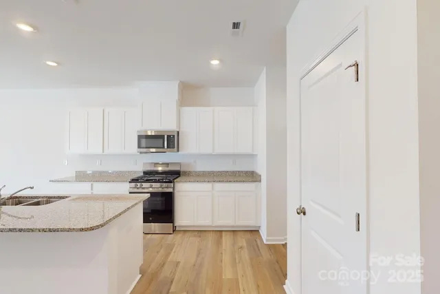 a kitchen with granite countertop a sink stove and refrigerator