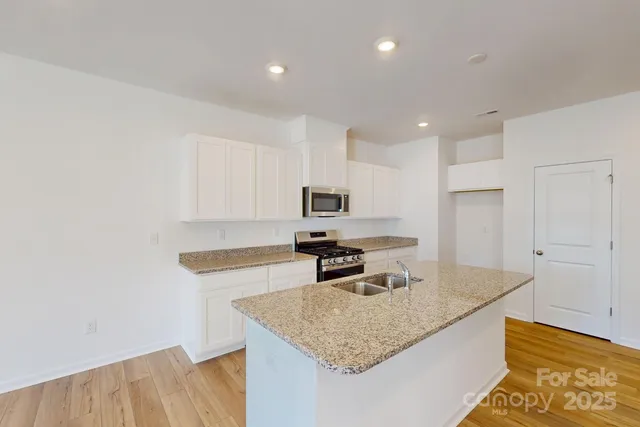 a kitchen with stainless steel appliances granite countertop a sink refrigerator and microwave