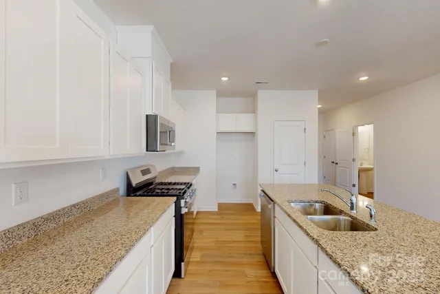 a kitchen with granite countertop a sink a counter top space and cabinets