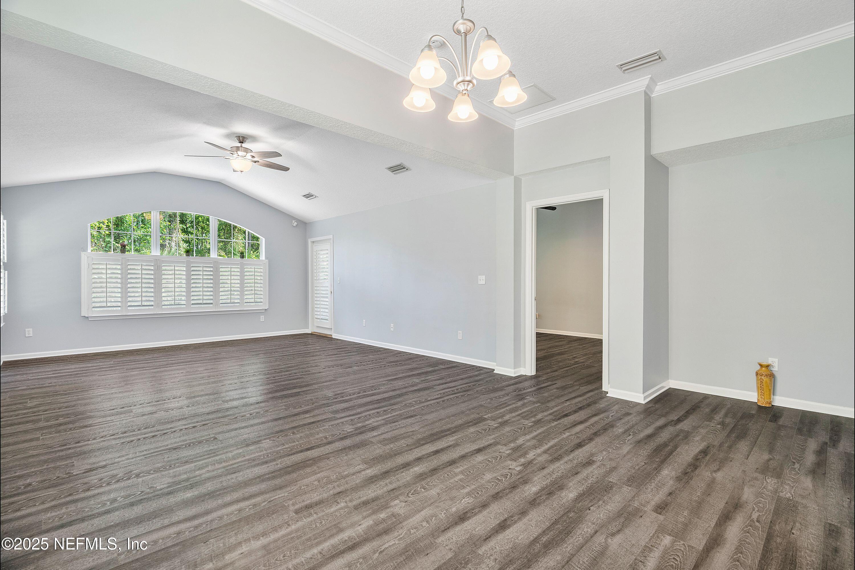 2120 Stone Creek Drive, Unit E Fleming Island, FL 32003 - Photo 12 of 66 an empty room with wooden floor chandelier fan and windows