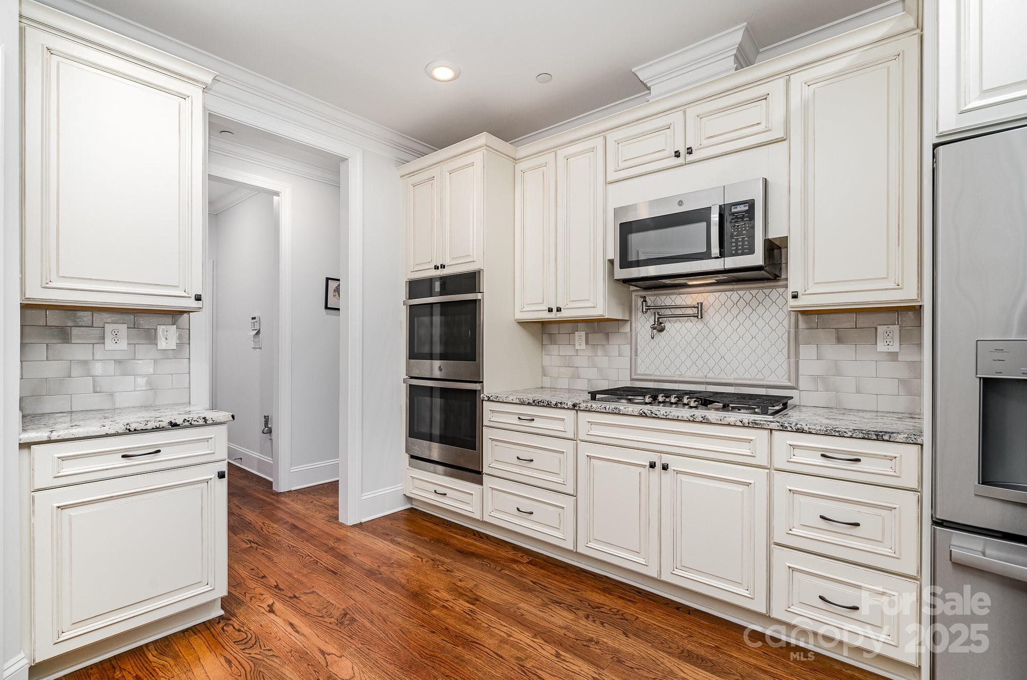 10874 Rise Lane Fort Mill, SC 29707 - Photo 19 of 48 a kitchen with stainless steel appliances white cabinets and a stove a oven with wooden floor