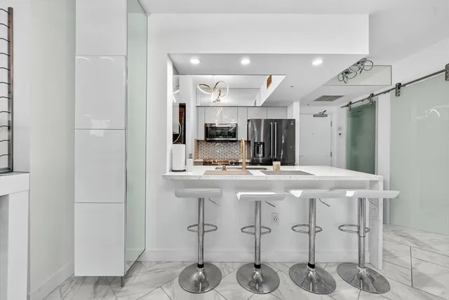 a kitchen with stainless steel appliances kitchen island granite countertop a refrigerator and a sink