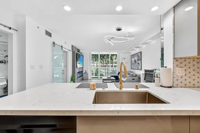 a kitchen with a sink a counter top space and living room view