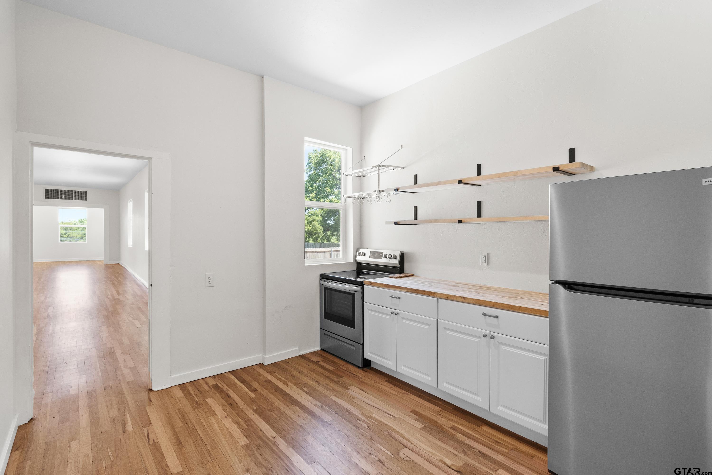 4456 Farm To Market Road 2767 Tyler, TX 75708 - Photo 19 of 46 a kitchen with white cabinets and wooden floor