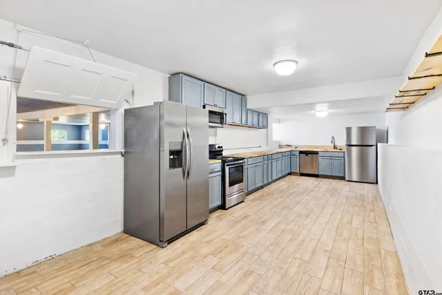 a large kitchen with stainless steel appliances a refrigerator and a stove top oven