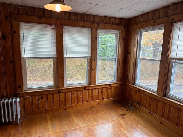 a view of an empty room with a window and wooden floor