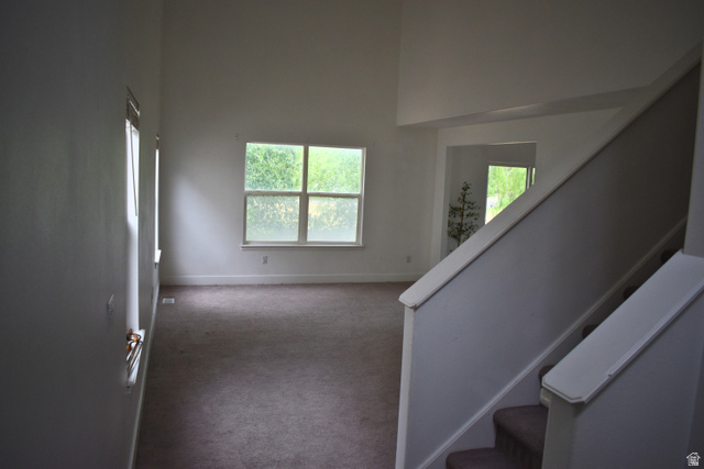 3327 East Windhover Road Eagle Mountain, UT 84005 - Photo 3 of 38 Open concept living space featuring a two-story ceiling, multiple windows, and carpet flooring