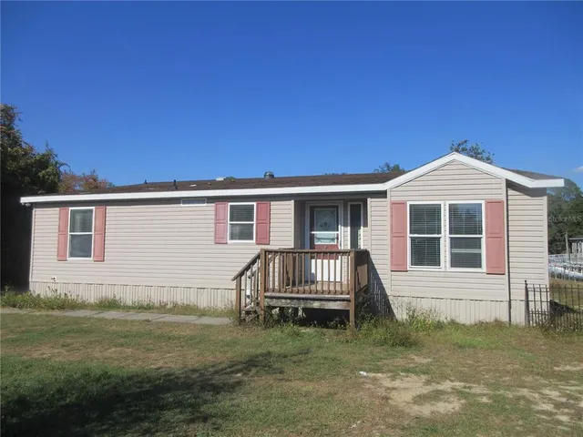 a view of a house with a wooden deck and a yard