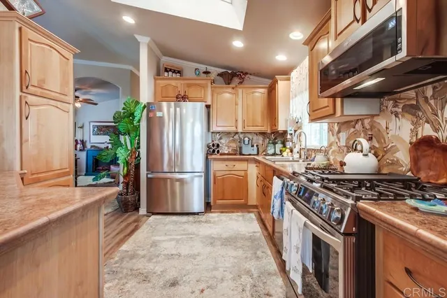 a kitchen with stainless steel appliances granite countertop a refrigerator a sink and white cabinets