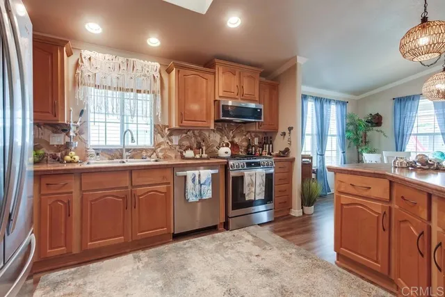 a open kitchen with a refrigerator a sink dishwasher a dining table and chairs with wooden floor