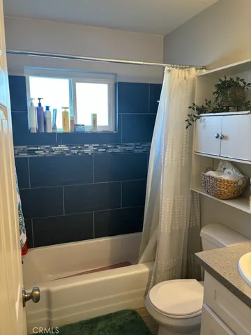 a bathroom with a granite countertop bathtub shower sink vanity and toilet