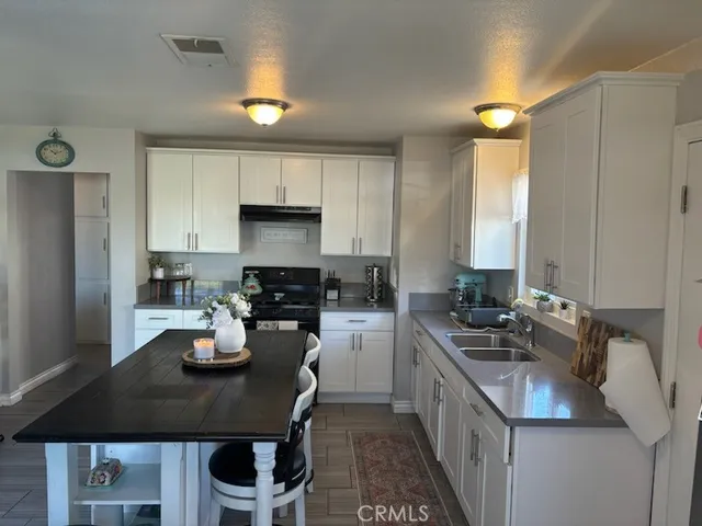a kitchen with a sink a stove cabinets and chairs