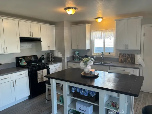 a kitchen with kitchen island granite countertop a sink cabinets and wooden floor