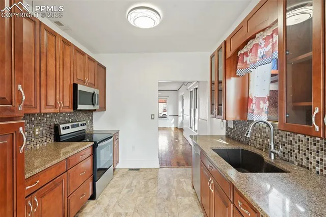 a kitchen with granite countertop a stove a sink and a microwave