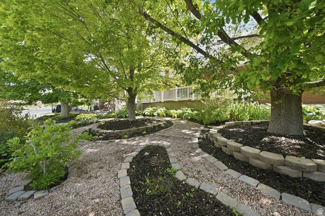 3120 North Apache Way Provo, UT 84604 - Photo 9 of 58 Landscaped exterior featuring a gravel pathway with paver edging, mature trees, and a tiered garden bed with dark mulch