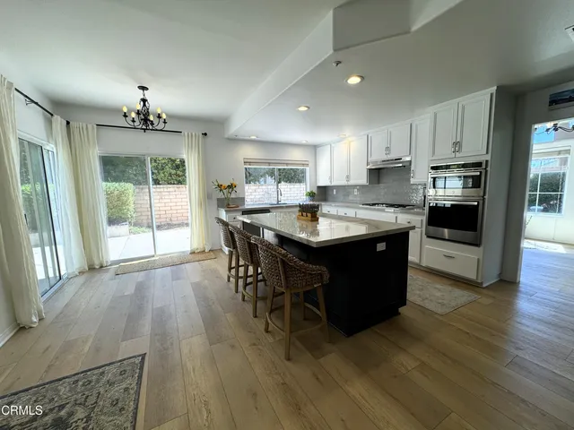 a kitchen with a stove a sink a refrigerator and a dining table with wooden floor