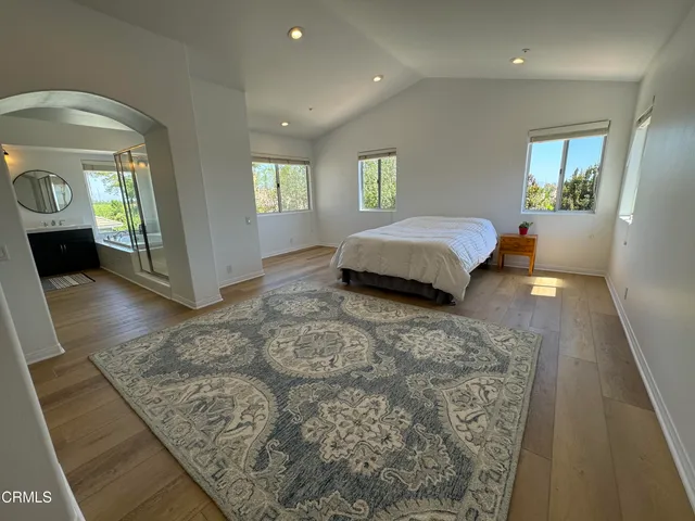 a spacious bedroom with a bed and dresser with mirror