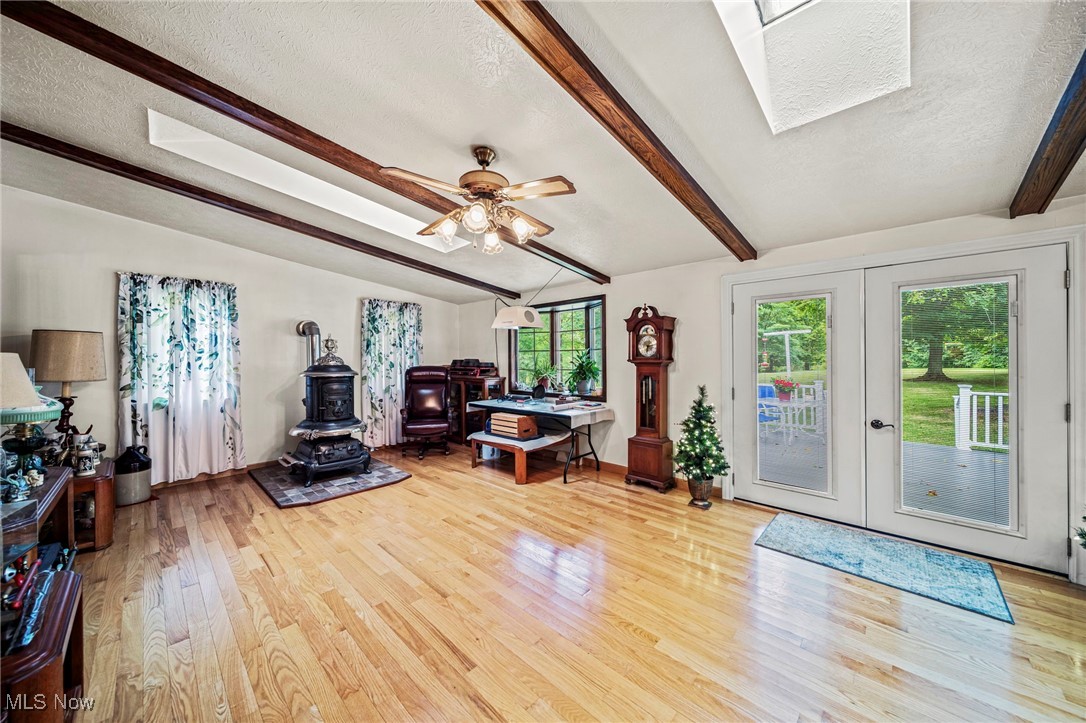 2921 Sexton Road Geneva, OH 44041 - Photo 27 of 43 Living area featuring a wood stove, light wood-style flooring, a ceiling fan, a skylight, and french doors