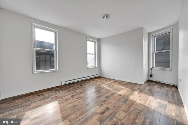 a view of an empty room with window and wooden floor
