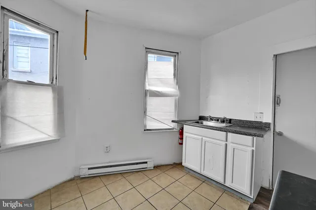 a kitchen with granite countertop a stove a sink and white cabinets