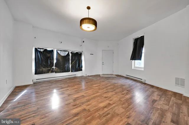an empty room with wooden floor and windows