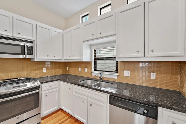 a kitchen with white cabinets and stainless steel appliances