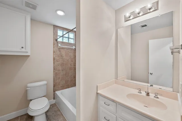 an empty room with chandelier fan and windows