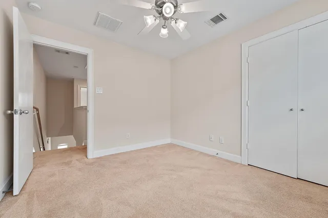 an empty room with windows and chandelier fan