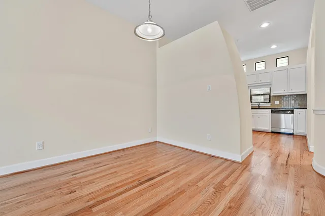 a view of an empty room with wooden floor and a ceiling fan