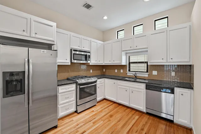 a kitchen with granite countertop white cabinets and stainless steel appliances