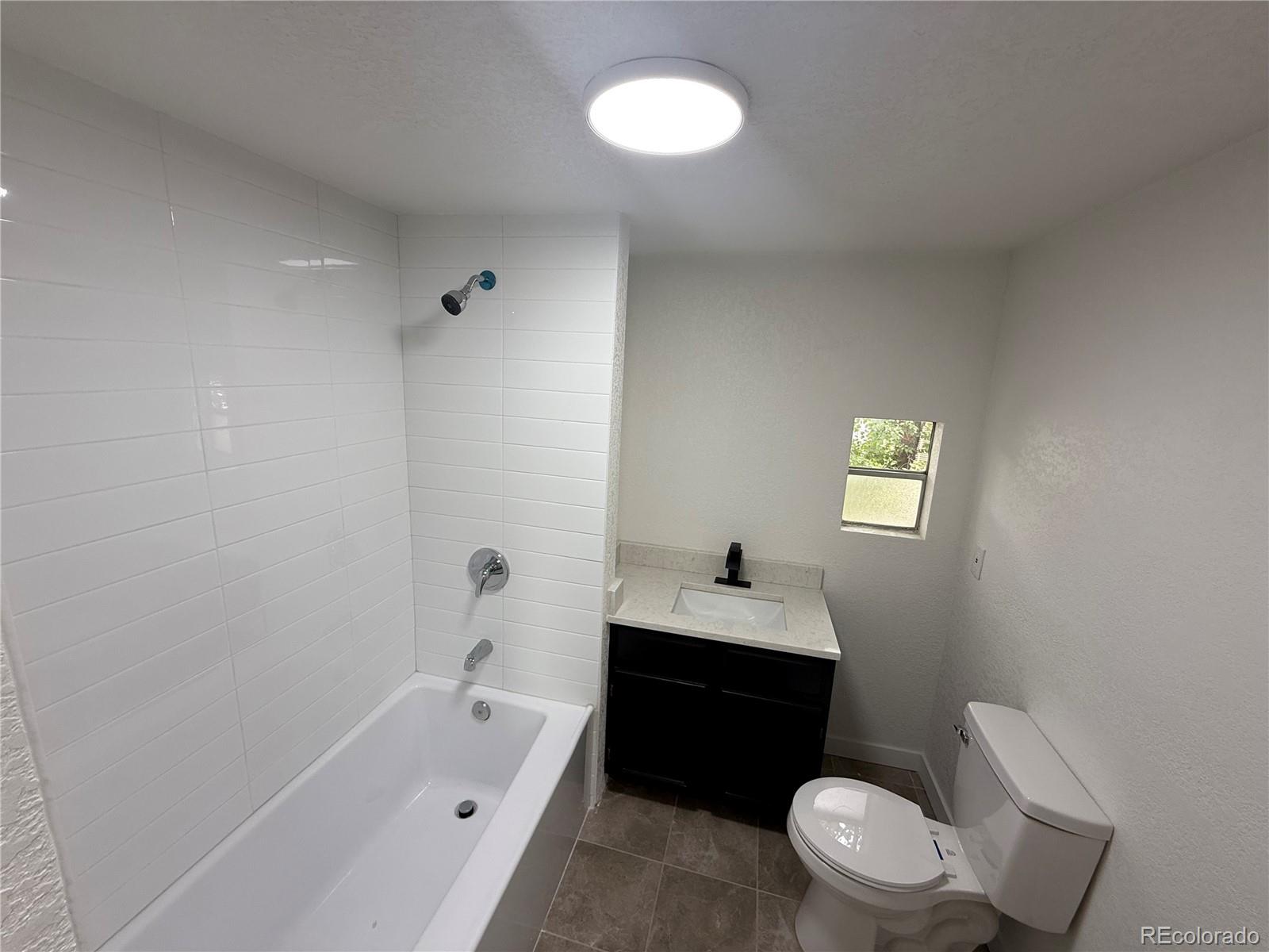 1045 Mac Davidson Circle Dacono, CO 80514 - Photo 16 of 32 a bathroom with a toilet sink a bathtub and a window