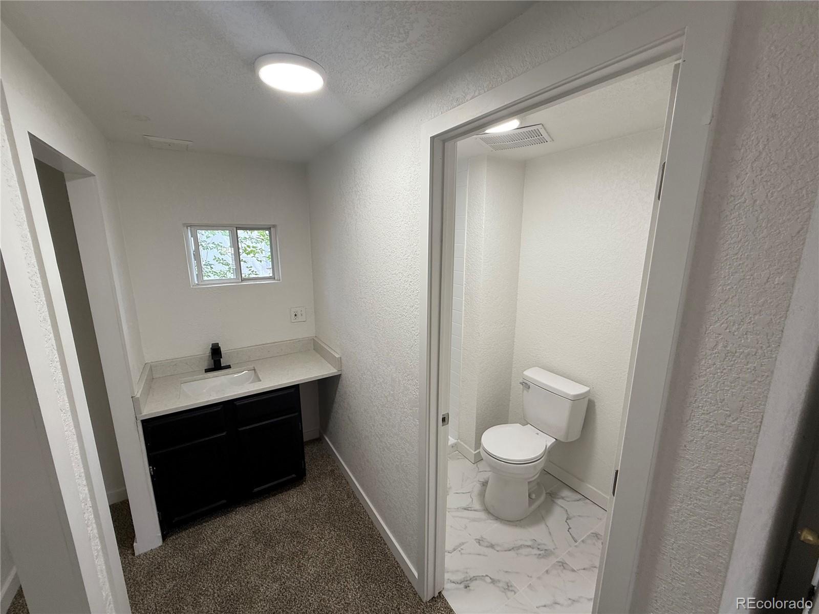 1045 Mac Davidson Circle Dacono, CO 80514 - Photo 18 of 32 a bathroom with a sink a toilet a shower and a window