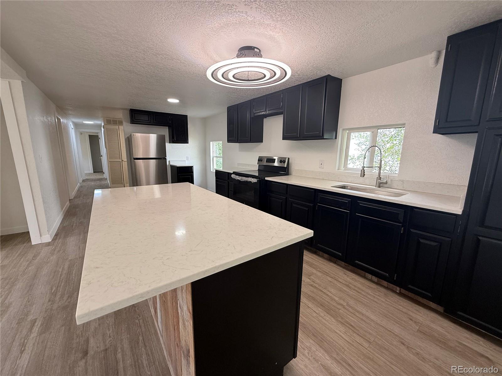 1045 Mac Davidson Circle Dacono, CO 80514 - Photo 2 of 32 a kitchen with a sink a stove a refrigerator cabinets and wooden floor
