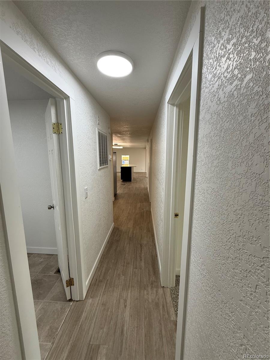 1045 Mac Davidson Circle Dacono, CO 80514 - Photo 21 of 32 a view of a hallway with wooden floor and staircase