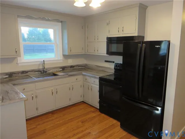 a kitchen with granite countertop stainless steel appliances white cabinets sink and window