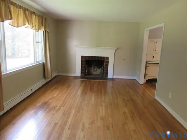 a view of an empty room with a window and wooden floor