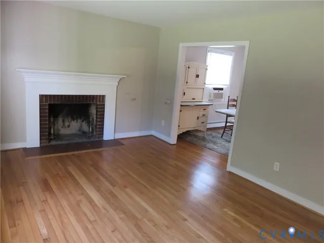 a view of a livingroom with wooden floor and a fireplace