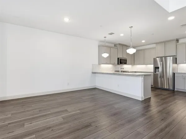 a large kitchen with a center island wooden floor stainless steel appliances and cabinets