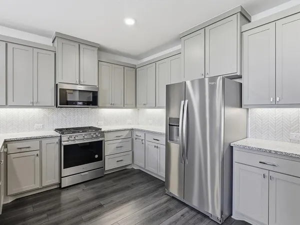 a kitchen with granite countertop white cabinets and stainless steel appliances