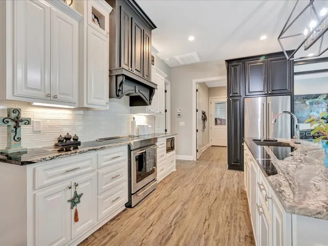 a kitchen with stainless steel appliances granite countertop a refrigerator a stove and a sink