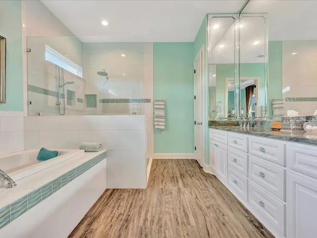 a spacious bathroom with a granite countertop double vanity sink a mirror and a shower